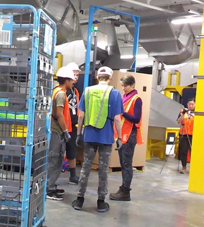 Marlena, a nonbinary person with deep pink, purple, and green hair and green eyeshadow, wearing a green and black striped dress, staring fiercely into the camera